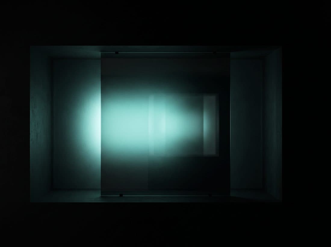 A pane of dark glass lit from behind with cold mint light — reading through the glass without reaching past it.