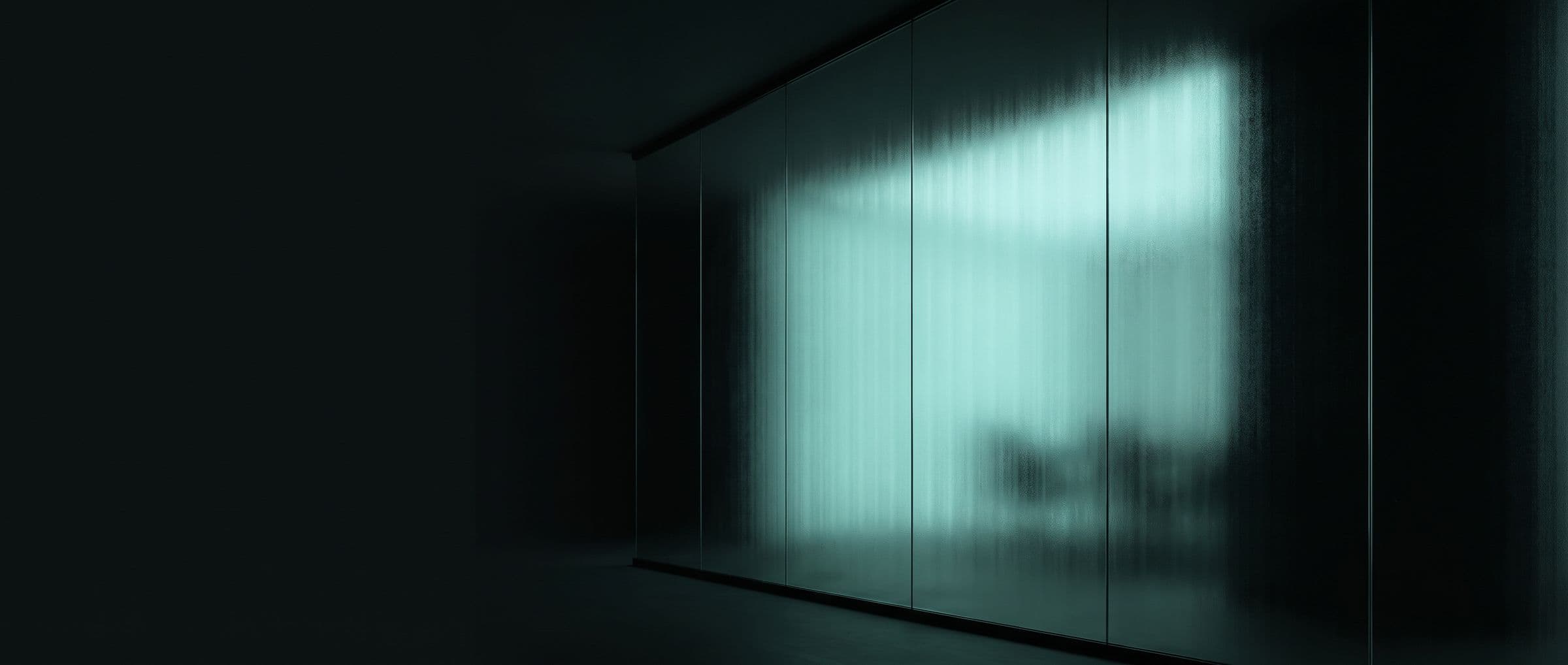 A wall of dark frosted glass with a cold mint light glowing behind it — something seen clearly but never touched.